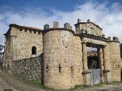 Entrada principal de una torre medieval con muros de piedra y un arco.