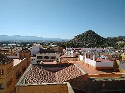 Tejados y casas en Vera con una colina en el fondo.