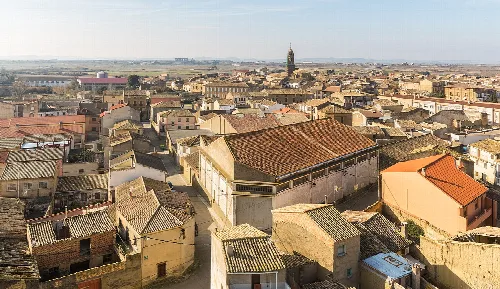 View of rooftops and streets of Sádaba with church in the distance.