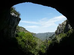 View of a natural space with vegetation and mountains, seen from a cave or tunnel in Capafonts.