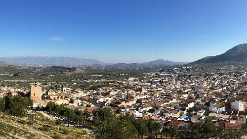 Panoramablick auf Jódar mit Bergen und Feldern im Hintergrund.