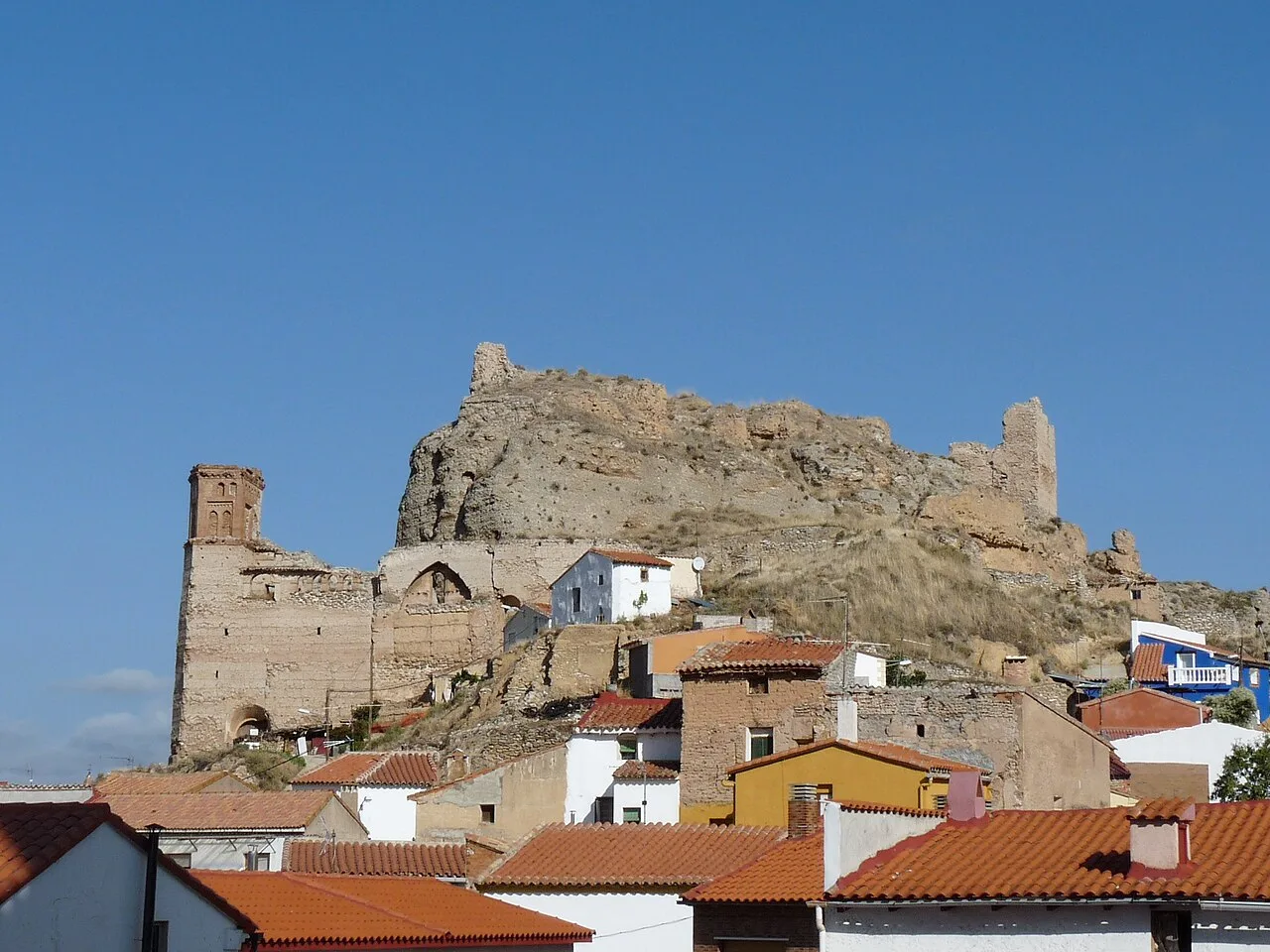 Ruinas del castillo y iglesia en Maluenda, con casas de tejado rojo.