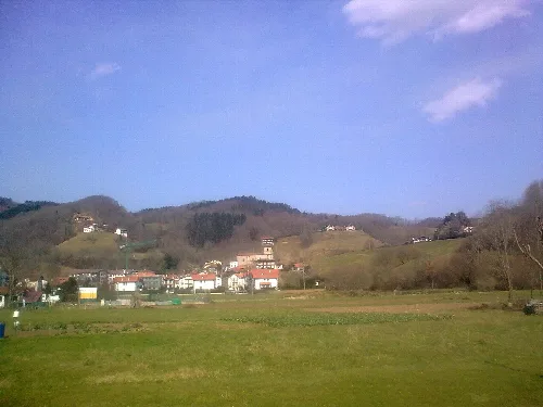 Rural landscape with hills, houses, and blue sky in Vera de Bidasoa, Navarra.