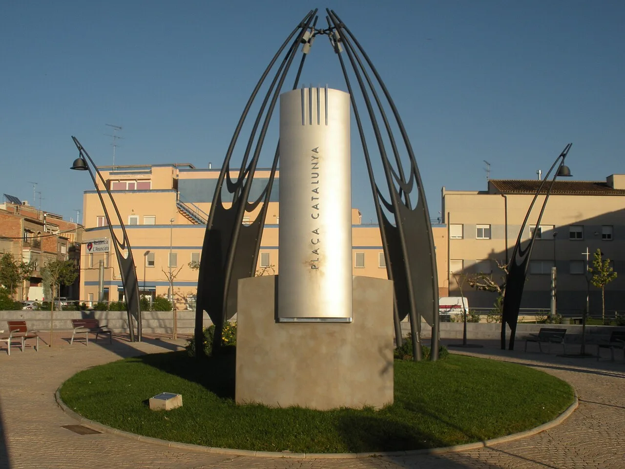 Moderne Skulptur mit Metallbögen und Monolith auf Junedas Platz.