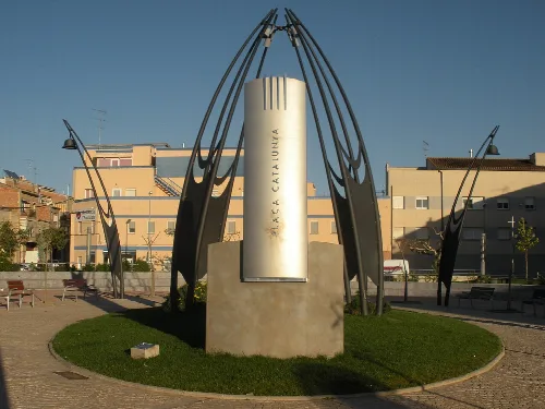 Moderne Skulptur mit Metallbögen und Monolith auf Junedas Platz.