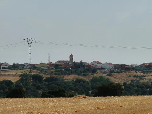 Panoramic view of Casa de Uceda with houses, church, and nature.