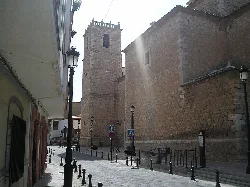 Church tower in Pedro Muñoz with street and lampposts.
