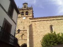 Torre de Santa María la Mayor de Ledesma con reloj y campanario en cielo azul.