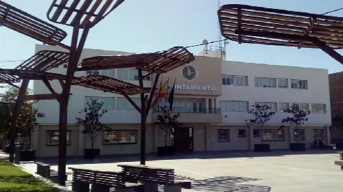 Gebäude des Rathauses von Armilla mit Bänken und Bäumen auf dem Platz.