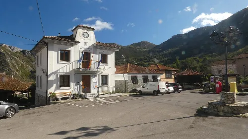 Edificio blanco con reloj y balcón en Villabré, Yernes y Tameza, Asturias.