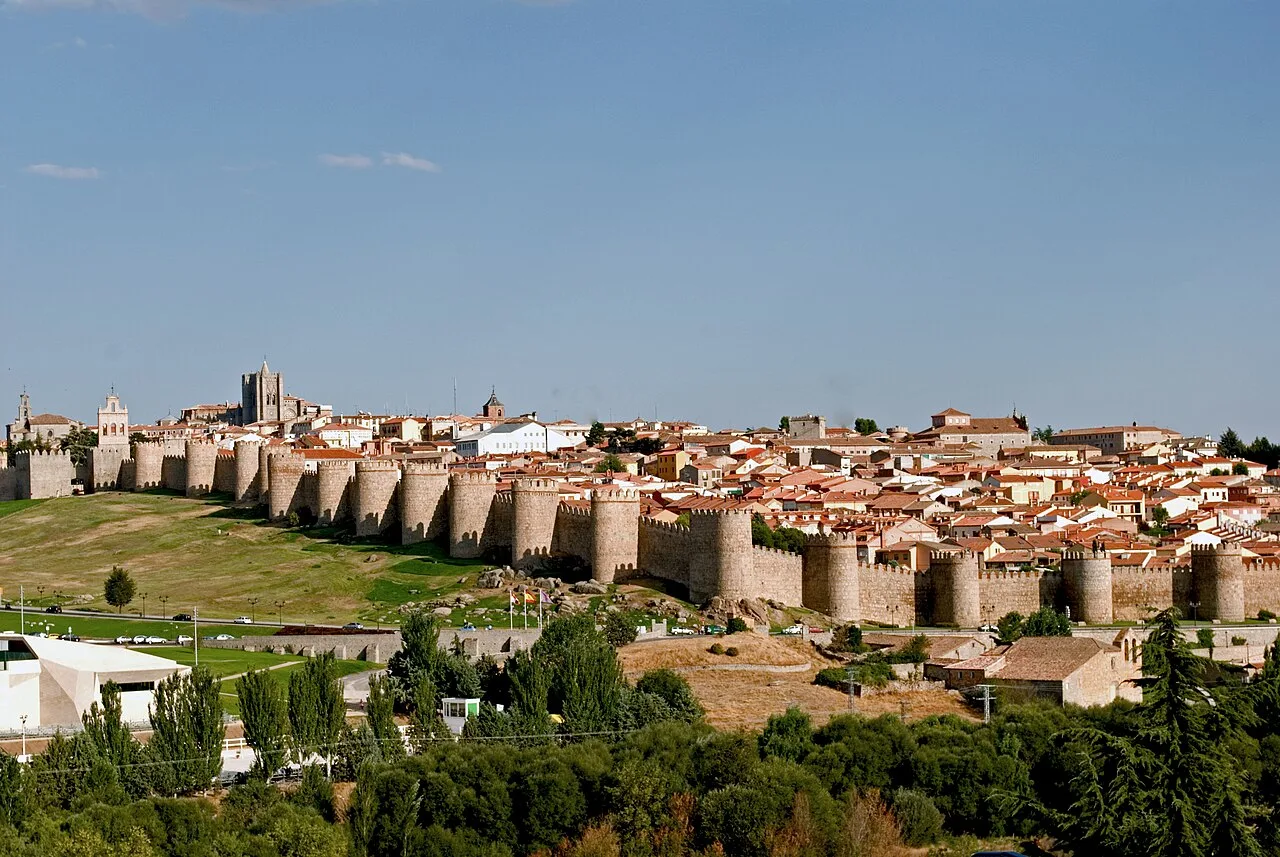 Steinmauern und Türme in Ávila unter blauem Himmel.
