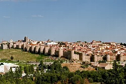 Stone walls and towers in Ávila under a blue sky.