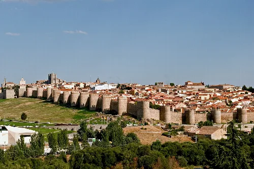 Steinmauern und Türme in Ávila unter blauem Himmel.