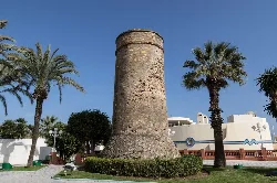 Runder Steinturm in einem Park mit Palmen und Gärten in Benalmádena.