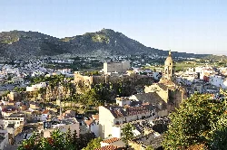 Vista de las murallas, iglesia y casco antiguo de Loja con montañas en el fondo.