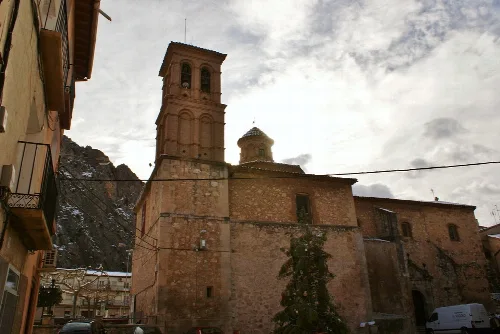 Stone church facade with tower and dome in Alhama de Aragón.