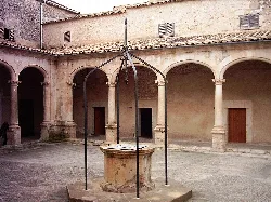 Cloister with well in the center and stone arches in Sineu.