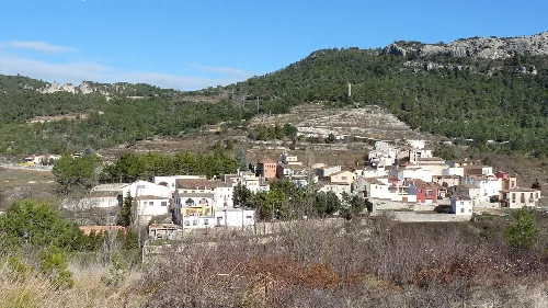 Vista de casas en un pueblo en una zona montañosa con vegetación.