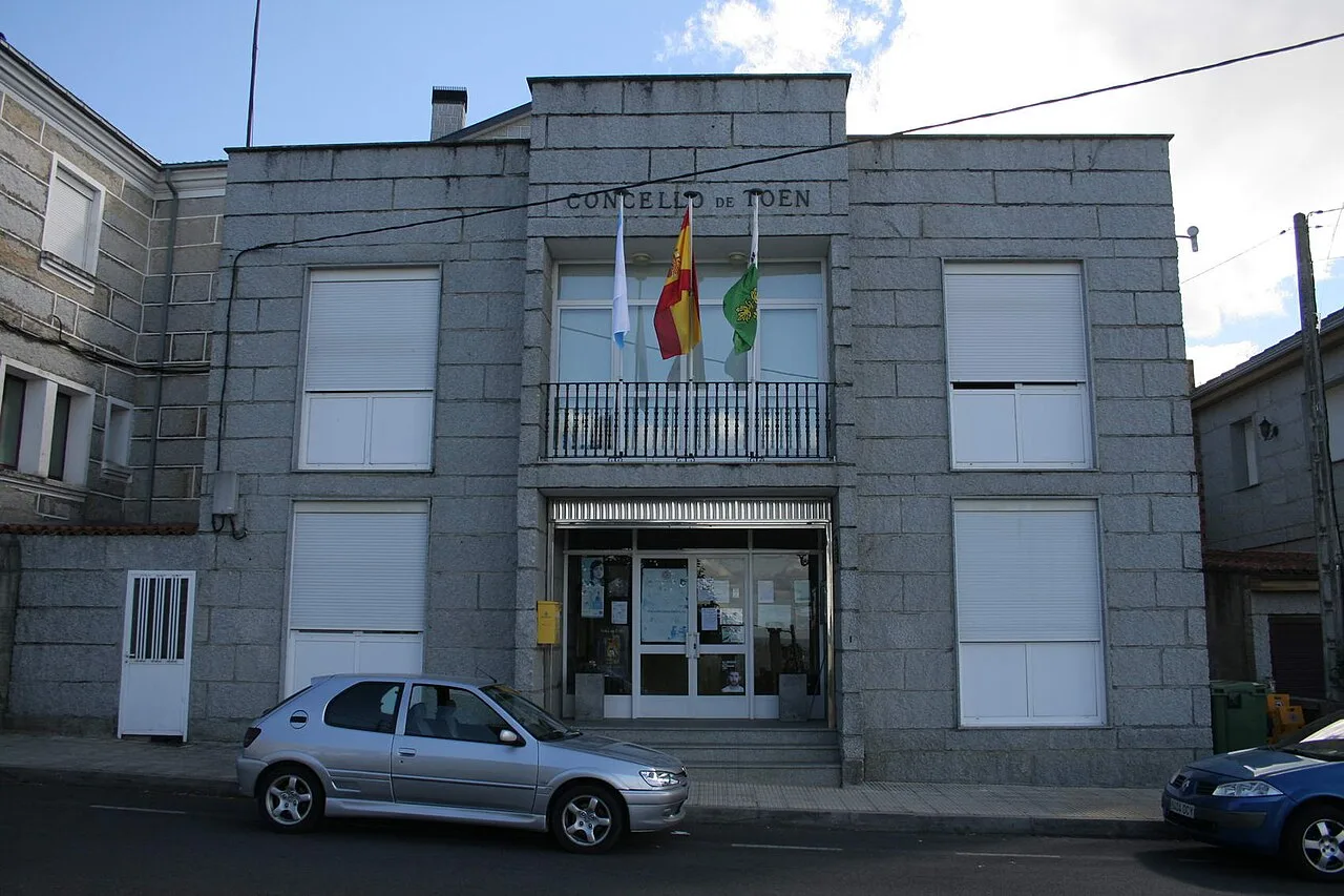 Edificio del ayuntamiento de Toén con banderas en la fachada.