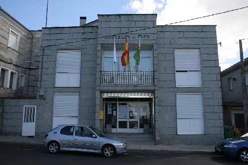 Gebäude des Rathauses von Toén mit Flaggen an der Fassade.