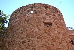 Torre redonda de piedra con una pequeña ventana en la parte superior.