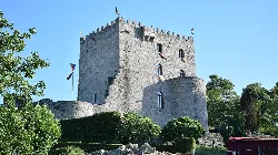 Steinernes Schloss mit Türmen und Mauern in einer grünen Umgebung in Alfoz.