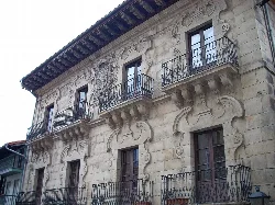 Fassade eines Gebäudes mit Eisenbalkonen und ornamentalen Details oben.