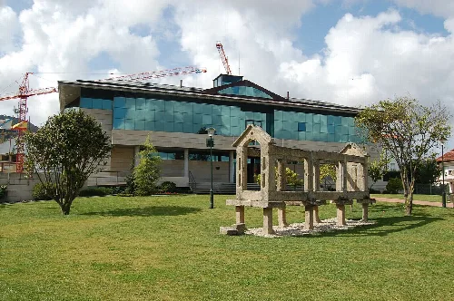Modern building with glass windows and stone structures in the foreground.