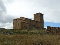 Kirche Santa María de Caracena in Soria, mit bewölktem Himmel und ländlicher Landschaft.