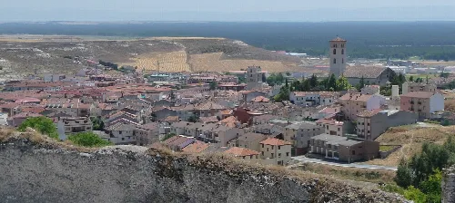 Panoramic view of Cuéllar from the castle, with rooftops and a church in the center.