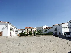 Plaza con casas blancas y un jardín en el centro en Albalá.
