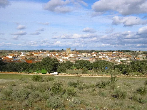 Paisaje rural con casas, árboles y un castillo en la distancia en Guadramiro.
