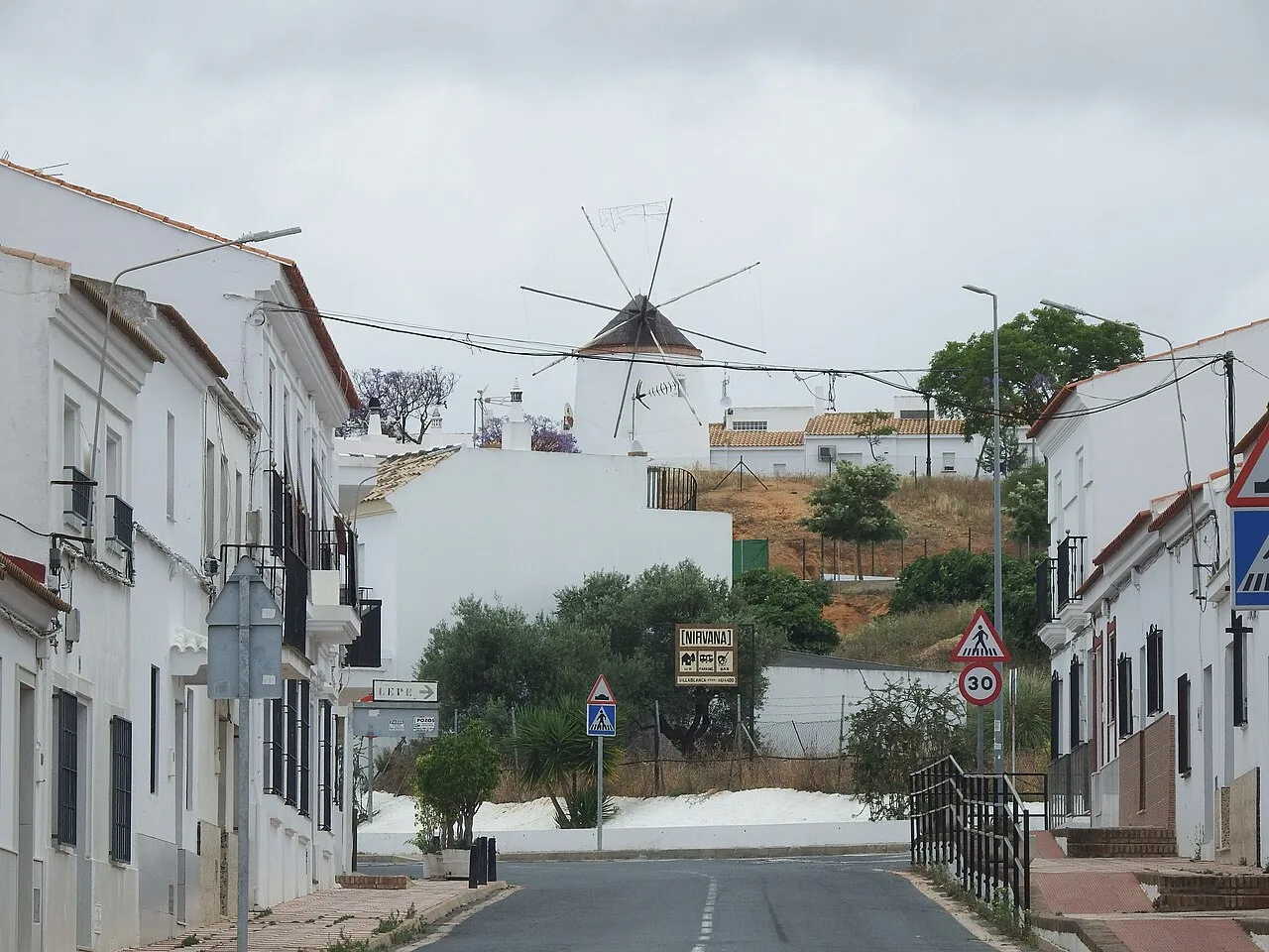 Straße in Villablanca mit weißen Häusern und Windmühle.