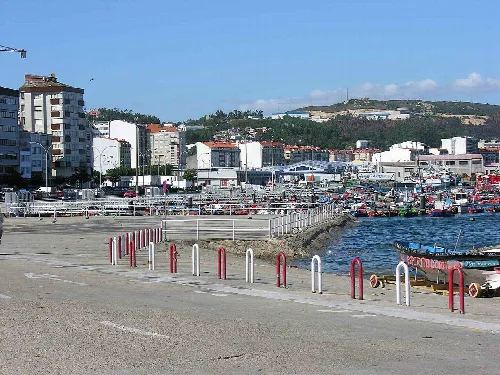Hafen und Strand in Ribeira mit Gebäuden und Hügeln.