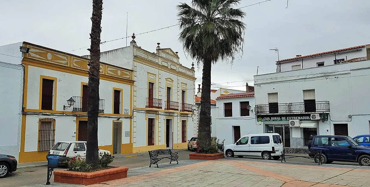 Platz mit weißen Gebäuden, Palme und Bänken in Higuera de Vargas.