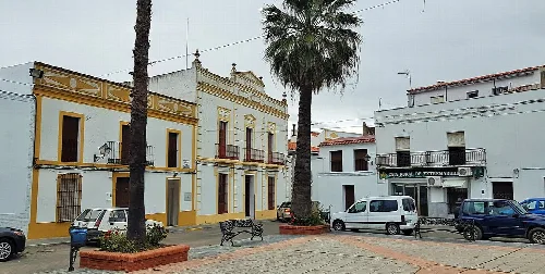 Platz mit weißen Gebäuden, Palme und Bänken in Higuera de Vargas.