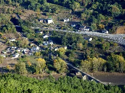 Vista aérea de Rairos con casas, vegetación y un puente sobre el río.