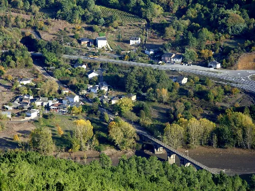Luftaufnahme von Rairos mit Häusern, Vegetation und einer Brücke über den Fluss.