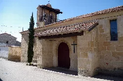 Iglesia de piedra con puerta de madera y cruz en la pared en Vallesa de la Guareña.