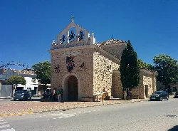 Stone church facade with blue bell tower and people at the entrance.