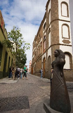 Fachada del teatro con escultura y personas en la calle.