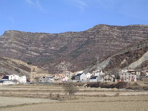 Dorf mit Häusern und Bergen im Hintergrund.