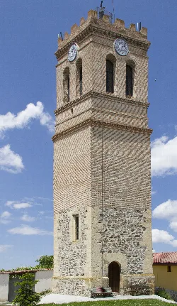Clock tower of Navas de Oro with clock at the top and brick structure.