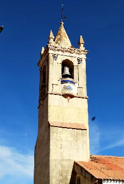 Torre de iglesia con campanario y tejado de tejas rojas.