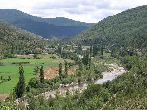 Aragón Subordán Fluss in einem Tal mit grünen Bergen und Feldern.