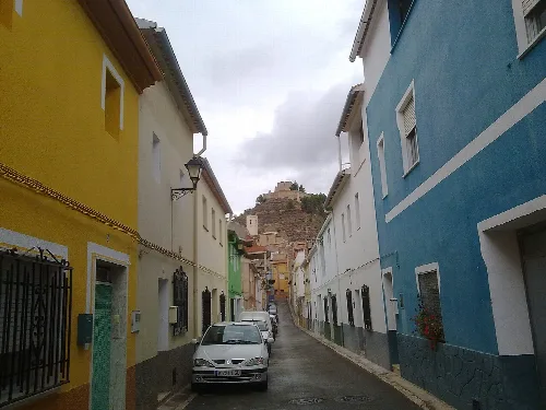 Calle Constitución, en el municipio de Jalance, Valencia, España. Al fondo de la imagen se aprecian la torre y la bóveda de la Iglesia y, en lo alto del cerro, el Castillo de Jalance.