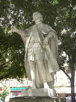 Statue of a king with cape and armor, standing, in Pamplona.