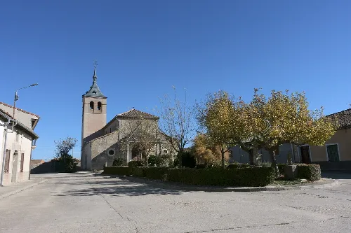 Church of the Assumption in Marazuela, Segovia, with tower and trees around.