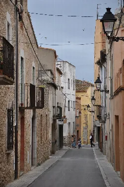 Calle del Carme con edificios antiguos y farolas en una calle estrecha.