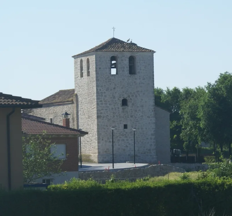 Steinerner Kirchturm mit Bogenfenstern und Ziegeldach.
